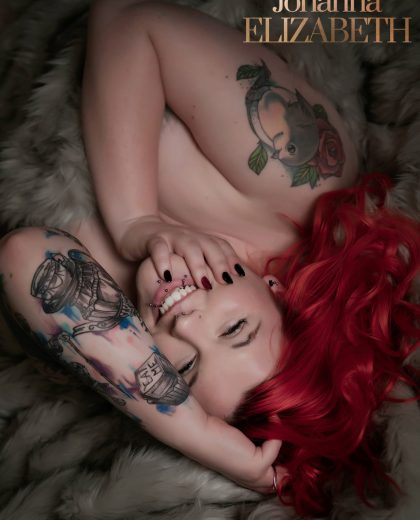 Woman with red hair and tattoos smiling to camera