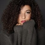 Woman with curly hair wearing a grey jumper