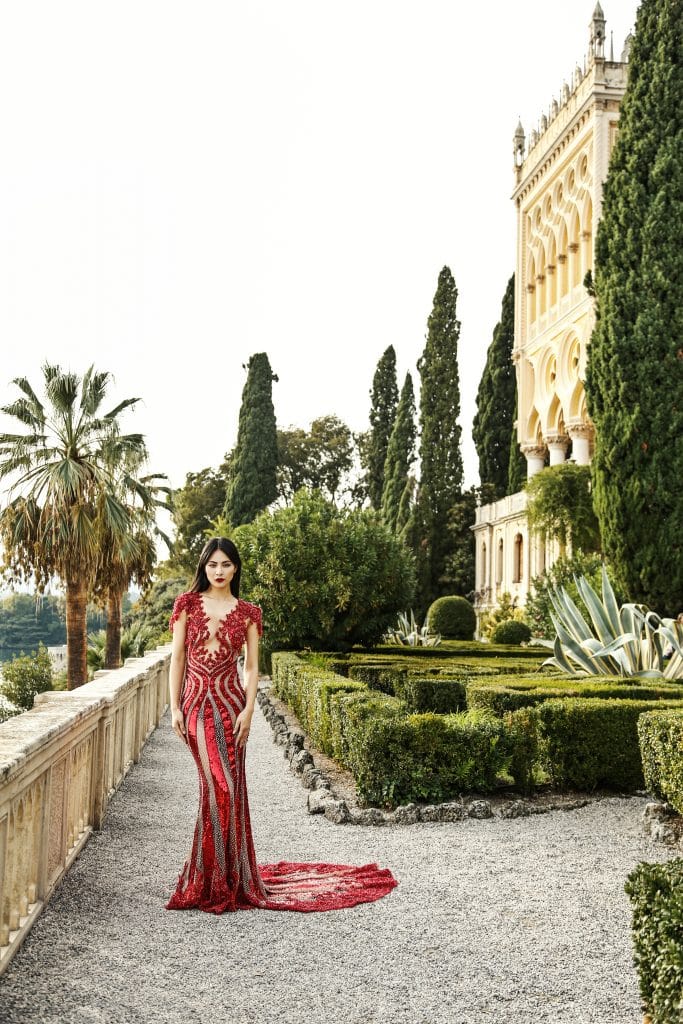 Woman in long red dress in a landscaped garden during a beauty and boudoir destination photoshoot