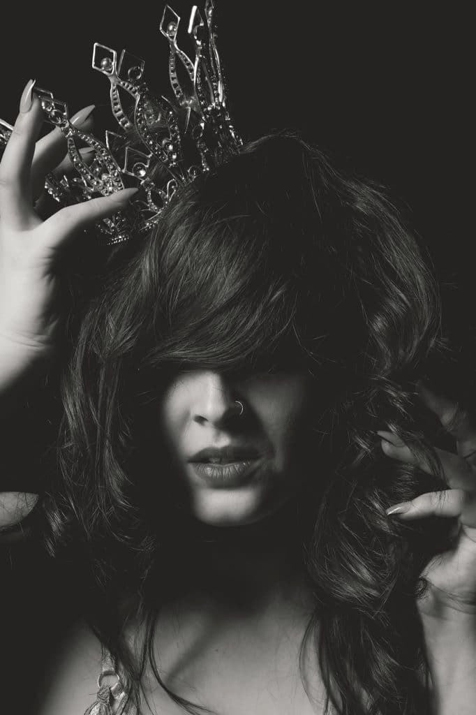 Brunette holding a crown on her head during a boudoir photoshoot