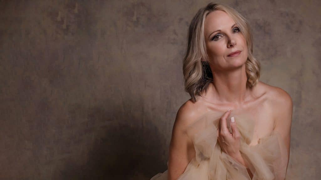 Atractive blonde woman wrapped in chiffon against a brown backdrop